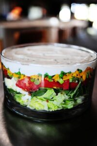 Une salade étagée colorée parfaite pour les repas-partage et les pique-niques. C'est une salade printanière simple et belle, et un aliment de base des repas-partage et des déjeuners dans ma région du pays. Vous pouvez varier les ingrédients selon vos goûts et ce que vous avez dans votre frigo, et vous pouvez l'agrémenter un peu d'herbes fraîches, de gorgonzola, tout ce qui fait voler votre jupe ! Les ingrédients standard de la plupart des salades en couches sont de la laitue ou des épinards (ou les deux !), Des œufs durs, du bacon émietté, du fromage râpé, des oignons verts et des pois verts, qui sont disposés en couches dans un joli bol en verre afin que les couches puissent être vues dans tous les sens. leur beauté colorée.